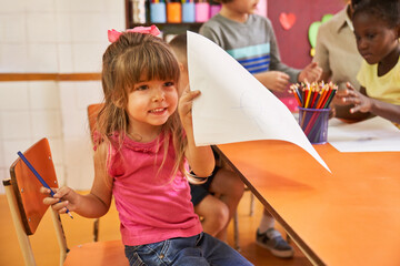 Little girl proudly shows a sheet with a drawing