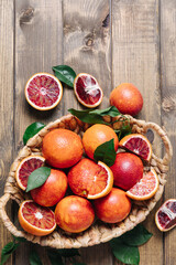 Obraz na płótnie Canvas Composition of pile of blood oranges in a basket on a wooden table background. Flat lay, top view, copy space