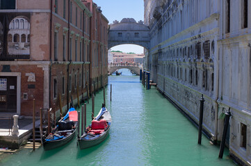 Fototapeta na wymiar romantic idyllic view of gondolas moored in narrow canal by renaissance facade of Doge's Palace and Ponte de i Sospiri