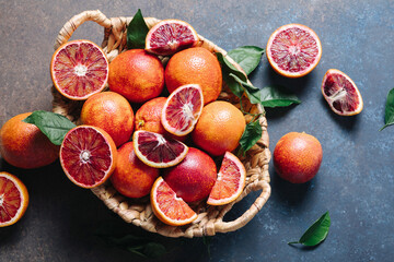 Composition of pile of blood oranges in a basket on a blue table background. Flat lay, top view,...