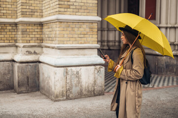 Young beautiful woman using a smartphone outside on a rainy day