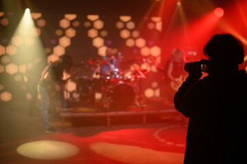 Silhouette of a photographer taking shots of a musicians on a stage
