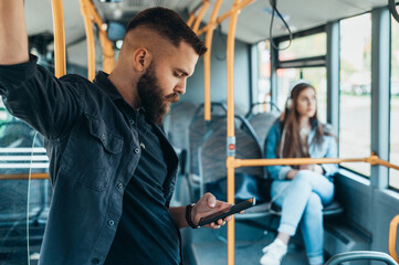 Man using a samrtphone while standing in a moving bus