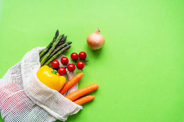 Buntes rohes Gemüse in einer wiederverwendbaren Einkaufstasche auf einem isolierten grünen Hintergrund. Gesunde Ernärhung, Diät.