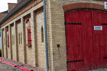 Closeup shot of a garage building with red wooden gates and windows
