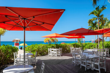 Beach cafe in Caribbean island in Montego bay, Jamaica. Red umbrellas and white table in beach Caribbean restaurant. 