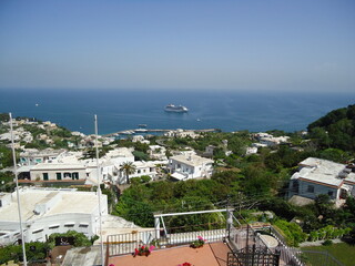 Blick auf das Mittelmeer und die Küste von Capri, sowie ein vor ihr ankerndes Kreuzfahrtschiff.
