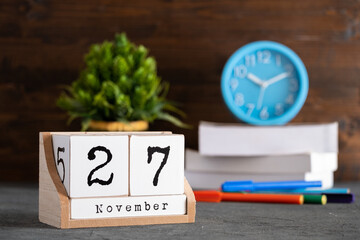 November 27th. November 27 wooden cube calendar with blur objects on background.