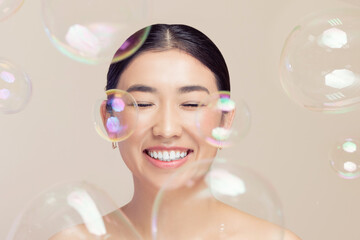 Fashion Asian happy young woman on background soap bubbles, fake eyelashes and makeup