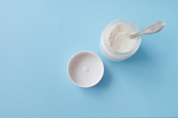 Homemade crockpot greek yogurt in glass jars on light blue background.