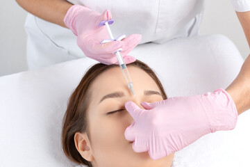 Cosmetologist makes rejuvenating anti wrinkle injections on the face of a beautiful woman. Female...