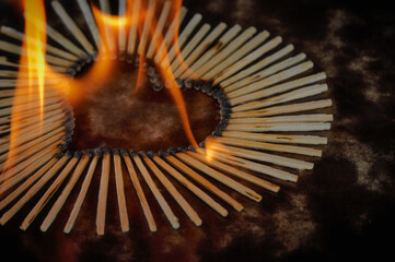 Burning heart made of matches on a dark background