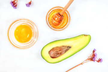 Natural skin care products, top view ingredients avocado, egg and honey on white background
