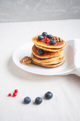 Freshly cooked delicious pancakes with honey, walnut, raspberries and blueberries for breakfast.