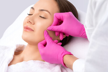 A procedure for cleansing the skin of the face from blackheads and acne. Cosmetologist treats problematic skin of a young woman's face in a beauty salon. Aesthetic cosmetology and makeup concept.