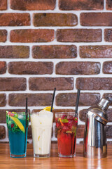 Citrus and raspberry lemonades, Piña colada and a shaker on a wooden table in a cafe