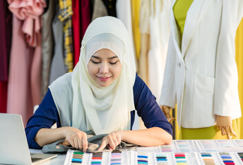 Muslim seamstress comparing fabric with samples