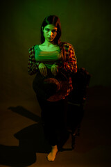 Fototapeta na wymiar A girl in a plaid shirt with a cowboy hat illuminated by multicolored light