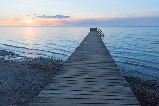 sunset beach scenery in light pastels, wooden boardwalk and beautiful sea