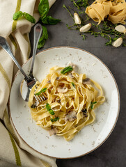 Pasta fettuccine with mushrooms and fried chicken ham in creamy cheese sauce on a light wooden background
