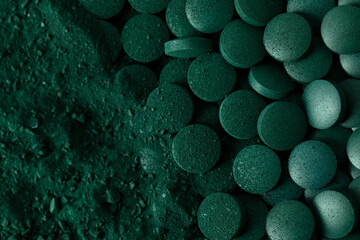 Green spirulina algae tablets and powder nutritional supplement macro close up top view.