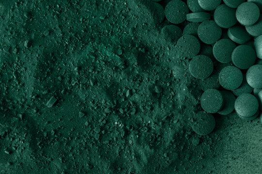 Green spirulina algae tablets and powder nutritional supplement macro close up top view.
