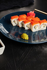 rolls in caviar on a blue plate on a black textured background