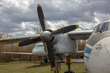 An-24 is a turboprop passenger aircraft for short and medium-haul lines. An old liner stands on the grass.