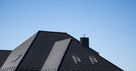 Brown corrugated metal profile roof installed on a modern house with a attic windows. The roof of...