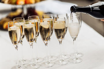 Many champagne glasses in a luxurious atmosphere. Stylish photo. Barman pours glass win champagne at new year party, wedding, business gathering