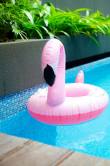 Hello summer. Pink inflatable flamingo in pool water for summer beach background. Trendy summer concept.
