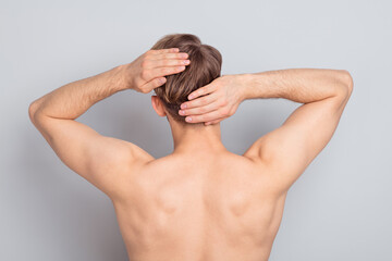 Backside photo of young blond man wash hair without clothes isolated on grey color background