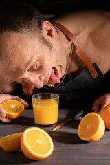 a white man in a dark kitchen apron with orange juice and oranges, a brutal still life in a low key, the process of making fresh juice