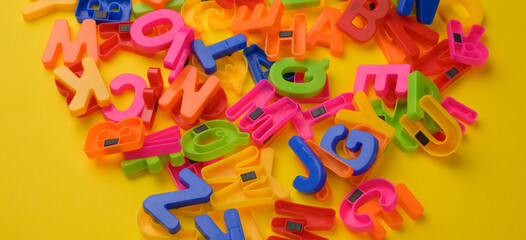 multicolored plastic english alphabet letters with magnet on yellow background