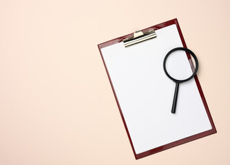 folder with blank white sheets and a black magnifier on a beige background. Background for...