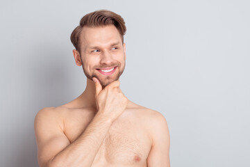 Photo of curious muscle blond hairdo guy hand face look empty space without clothes isolated on grey color background