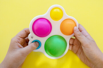 colorful antistress sensory toy fidget push pop it in kid's hands - obrazy, fototapety, plakaty