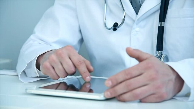 Doctor Sitting In Hospital Office And Using Digital Tablet Computer. Healthcare, Technology And Medicine Concept.