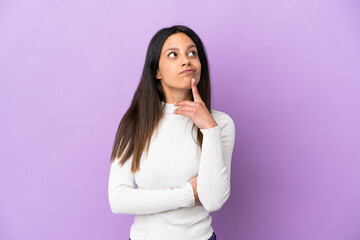 Young caucasian woman isolated on purple background having doubts while looking up