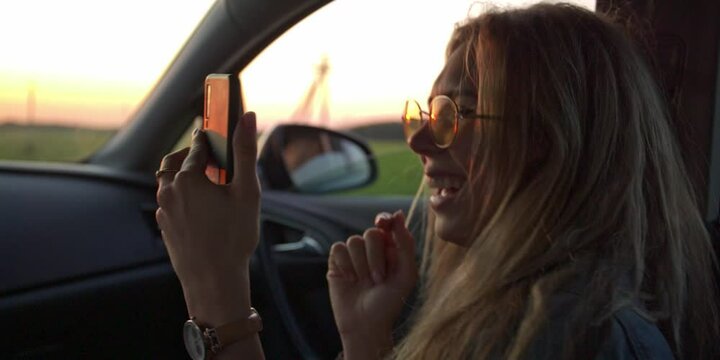 Fun Young Womens laugh and do a selfie and photo in Car. Slow Motion. Sunset on background. flares. travel concepte, Sunset