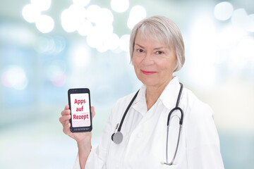 Smiling senior doctor with a smartphone showing the german text Apps auf Rezept. Translation: app...