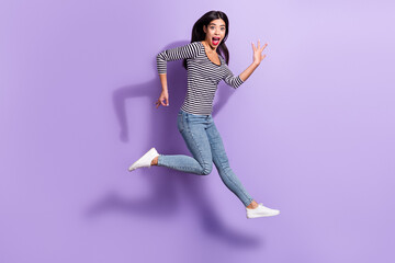 Full size photo of young shocked amazed funky girl jumping playing invisible guitar isolated on violet color background