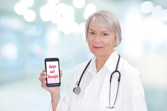 Smiling senior doctor with a smartphone showing the german text Apps auf Rezept. Translation: app on prescription.