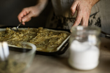 Male hands spreading onion pie filling on a baking sheet