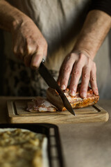 Male hands slicing smoked bacon on wooden board
