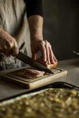 Fototapeta na wymiar Male hands slicing smoked bacon on wooden board