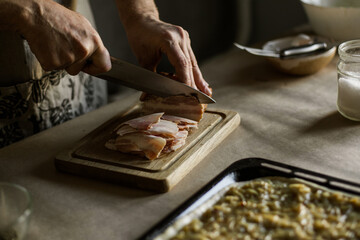 Fototapeta na wymiar Male hands slicing smoked bacon on wooden board