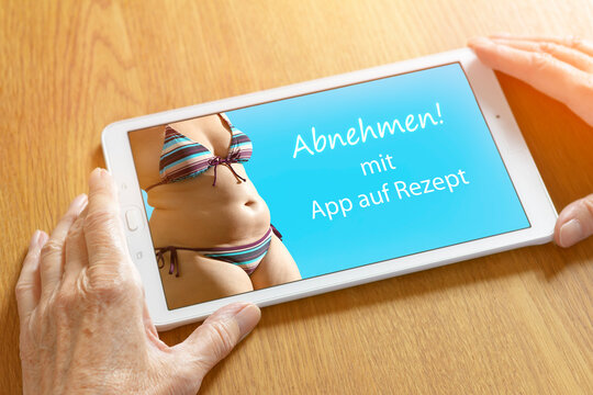 Smiling doctor showing a tablet computer with the german text: Abnehmen mit Apps auf Rezept, translation: slimming with prescription app.