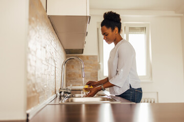 Woman using water and detergent, cleaning dishes.