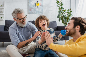 Smiling father and son with building blocks giving high five near grandfather